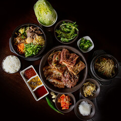 Korean BBQ set with a variety of meats including marinated dwaeji wang galbi pork ribs, bibimbap, and assorted vegetables, showcasing authentic Korean flavors