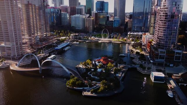 Cinematic aerial drone footage panning from left to right across Perth City, Western Australia, during a stunning sunset. The wide shot beautifully showcases Elizabeth Quay's iconic skyscrapers