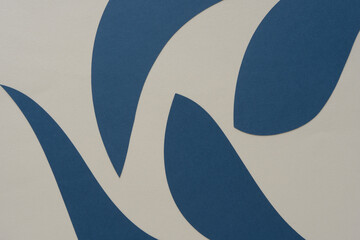 abstract navy blue machine-cut paper shapes with rounded and tapered edges on beige