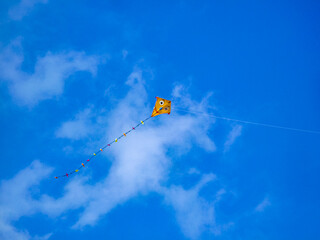 A yellow kite is flying high in the sky