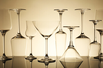 Many empty clean glasses on mirror surface against beige background