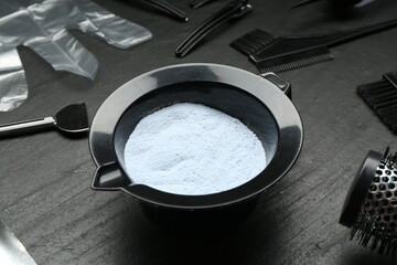 Bleaching powder and hairdresser's tools on black table, closeup