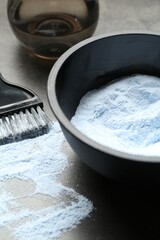 Bleaching powder and hairdresser's tools on grey table, closeup