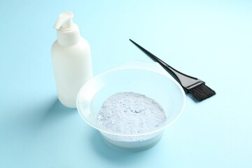 Bleaching powder and hairdresser's tools on light blue background