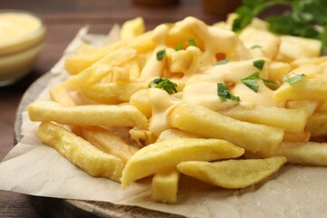French fries with cheese sauce and parsley on table, closeup