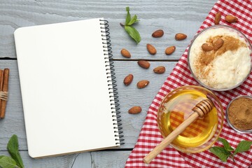 Blank recipe book, dessert and ingredients on grey wooden table, flat lay
