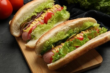 Tasty hot dogs with vegetables on black table, closeup