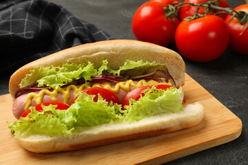 Tasty hot dog with vegetables on black table, closeup