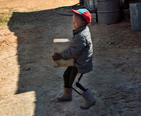 Child labor problems in Africa, african child working in the village carry bricks
