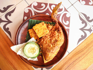 Penyet chicken is a variant of fried chicken in Indonesia, which is served by crushing chicken meat and a spicy chili sauce, served with sambal chili, tofu and cucumber slice. 