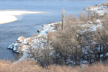 Zaporizhzhia, Ukraine. Beautiful winter on Khortytsia island, cold sunny day. Dnipro river, cliffs, snow-covered rocky river bank, small island among blue water.