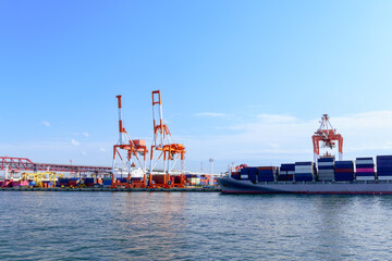 Large crane and cargo containers near Minato Bridge, sea port in Osaka bay. Logistic activities at Osaka pier, Japan.
