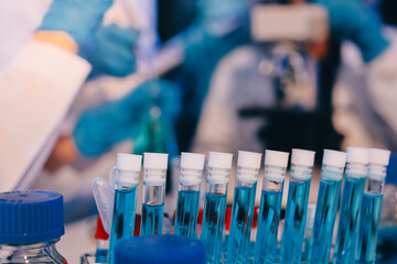 Two Asian women in a lab work on food research, using a microscope, petri dish, and test tubes filled with chemical solutions. They study vegetables, pork, and plants for GMO traits and nutrition.