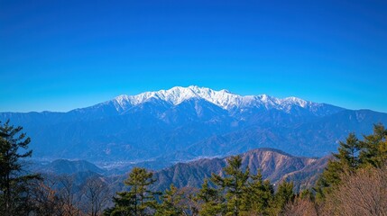 Majestic mountain range with snow covered peaks under clear blue sky