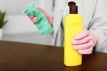 Woman polishing wooden table at home, closeup