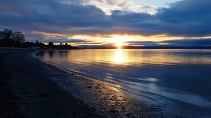 Sunset over a serene shoreline paints the sky with golden hues, reflecting on calm waters, capturing a peaceful, introspective moment in nature.