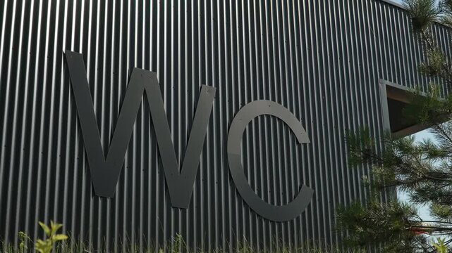 Large letters WC on ribbed dark grey wall of building, close-up. International designation of public toilet. Modern urban convenient infrastructure.