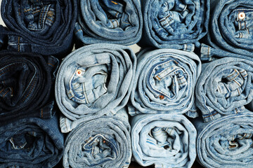 Different stylish rolled jeans as background, top view