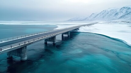 Obraz premium Stunning Aerial View of a Bridge Over a Turquoise Winter River in a Snow-Covered Mountain Landscape