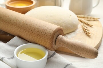 Rolling pin and different ingredients on light wooden table, closeup