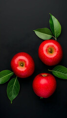 Obraz premium Three ripe red apples with green leaves on a dark background