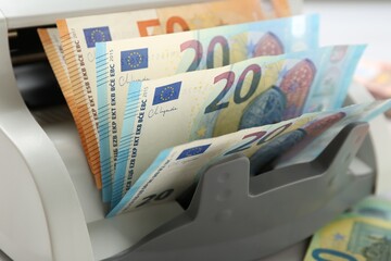 Money counter machine with euro banknotes on table, closeup
