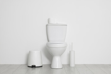 Toilet, brush and necessities near white wall