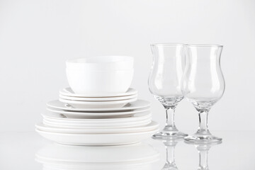 Different clean dishware and glasses on light background