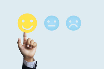 A businessman's hand reaches out to touch a smiley face icon to express satisfaction or feedback on a product or service or to express a feeling of being happy at work.