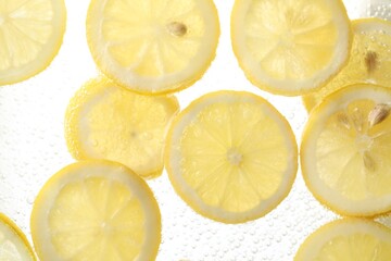 Soda water with lemon slices as background, closeup