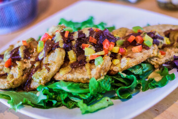 fried green tomatoes on a bed of mixed greens topped with black bean salsa