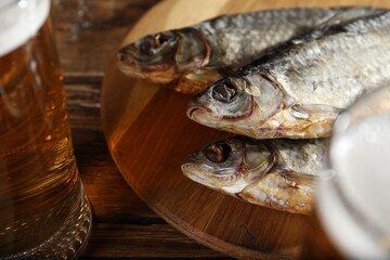 Dried fish and beer on wooden table, closeup
