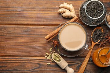 Aromatic Masala tea in cup, spices, dry leaves and honey on wooden table, flat lay. Space for text