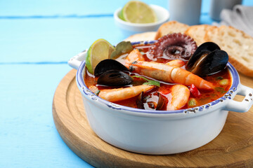 Delicious seafood soup in bowl on blue wooden table, closeup