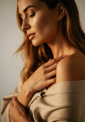 Elegant woman with long hair gently touching her shoulder in soft light
