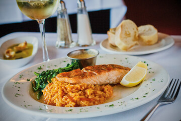 seared salmon fillet on a bed of tomato risotto with a side of sautéed spinach