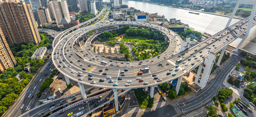 Aerial view of Shanghai highway interchange with heavy car traffic, skyscrapers and bridge infrastructure, the Huangpu River with urban transport