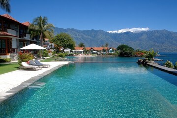 Fototapeta premium Resort scenery. Pool, ocean, and mountains view. Beach chairs, building, plants under blue sky