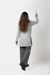 Woman from behind with long brown hair, on white background, points with finger in upper right corner.