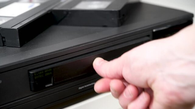 Male hand inserting VHS tape into VCR video player