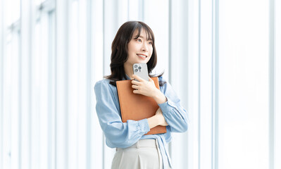 Obraz premium スマートフォンとバインダーを持つ笑顔の女性