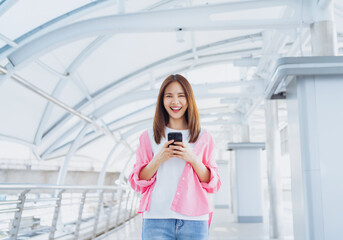 Fototapeta premium Young Asian woman using social media on smartphone in a urban city. fast connection, checking message on apps outdoors.