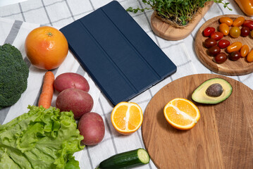 technology in the kitchen: vegetables and greens are on the table next to the tablet