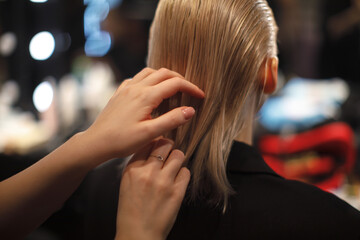 professional hairstylist carefully combs sleek blonde hair in a stylish salon. Precision haircut and beauty care in a modern setting