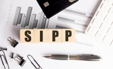 Wooden blocks with abbreviation sipp on financial documents with charts, credit card