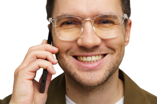 Smiling man with glasses talking on phone in a friendly and relaxed manner, indoors during the day
