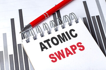 Notebook with text atomic swaps on financial charts with red pen representing cryptocurrency