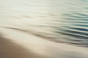 Sunset light reflects softly on the rippling edge of the sea in abstract motion.