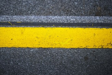 Yellow road marking. Asphalt texture. Traffic line. Street detail.

