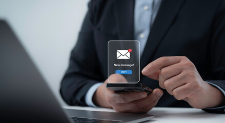 Businessman using a smartphone receives a new message notification. The image represents digital communication, online messaging, and modern email technology